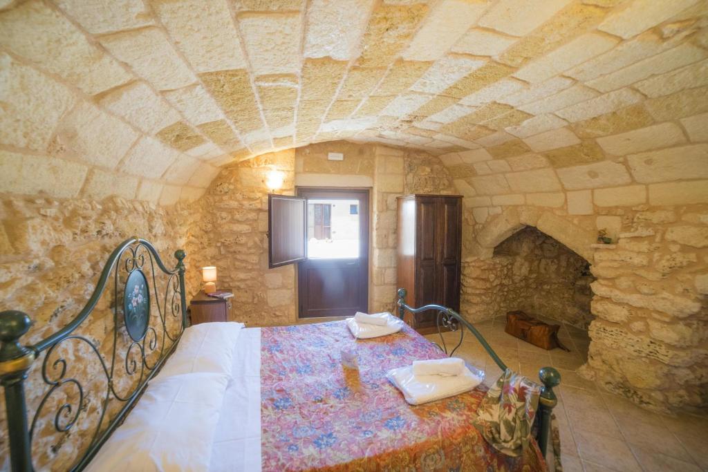 une chambre avec un lit dans un mur de pierre dans l'établissement Masseria Relais Saraceno With Pool - Happy Rentals, à Melendugno