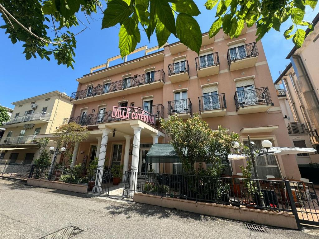 un bâtiment rose avec une clôture devant lui dans l'établissement Hotel Villa Caterina, à Rimini