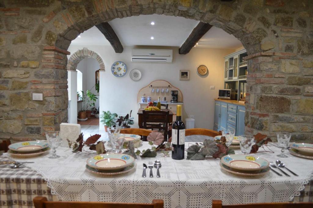 une table de salle à manger avec une nappe blanche et une pièce avec une cuisine dans l'établissement Villa Podere Terrena, à Gaiole in Chianti