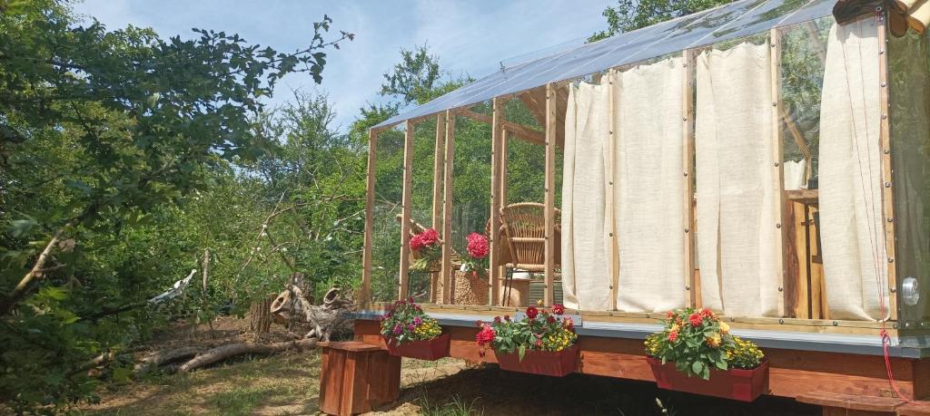 une maison en verre avec des fleurs sur son côté dans l'établissement Insolite Cabane du Rêveur, à Pagny-sur-Moselle