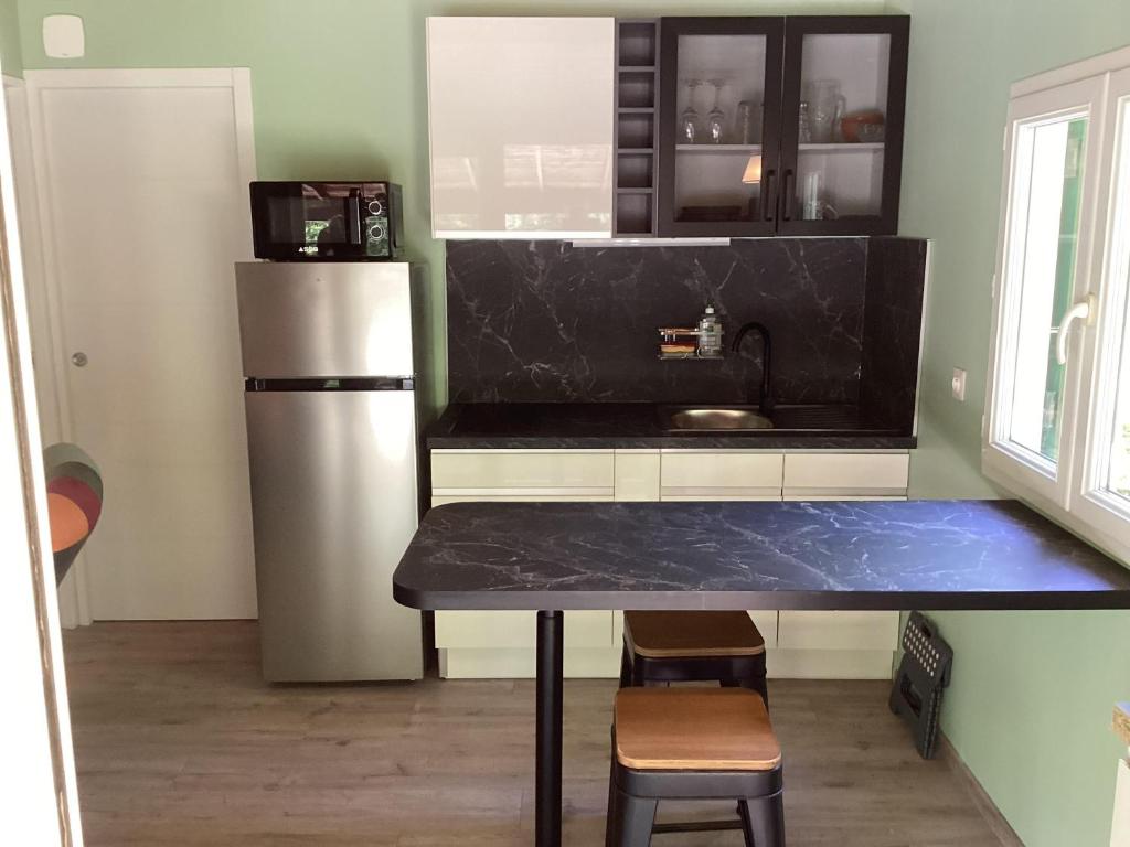 Il comprend une cuisine équipée d'un comptoir noir et d'un réfrigérateur. dans l'établissement Chalet de luxe bord de riviere, à Pont-de-Labeaume