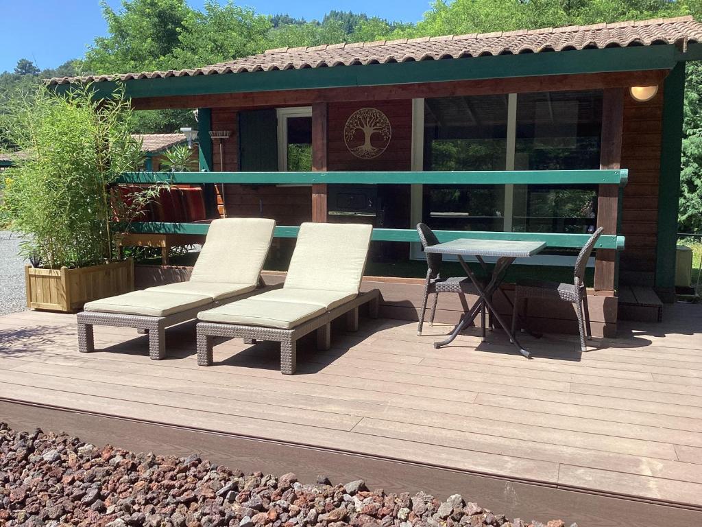 une terrasse avec des chaises, une table et une maison dans l'établissement Chalet de luxe bord de riviere, à Pont-de-Labeaume