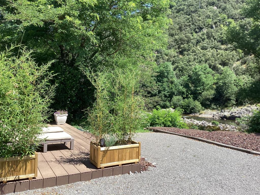 un banc assis sur une passerelle dans un jardin dans l'établissement Chalet de luxe bord de riviere, à Pont-de-Labeaume 2 autres photos