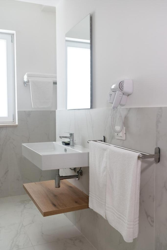 une salle de bain avec un lavabo, un miroir et des serviettes dans l'établissement Hotel Diadema, à Diamante 82 autres photos
