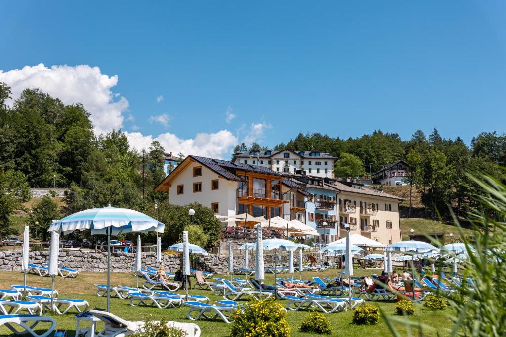 - un groupe de chaises et de parasols en face du complexe dans l'établissement Bazzario Loft, à Lavarone