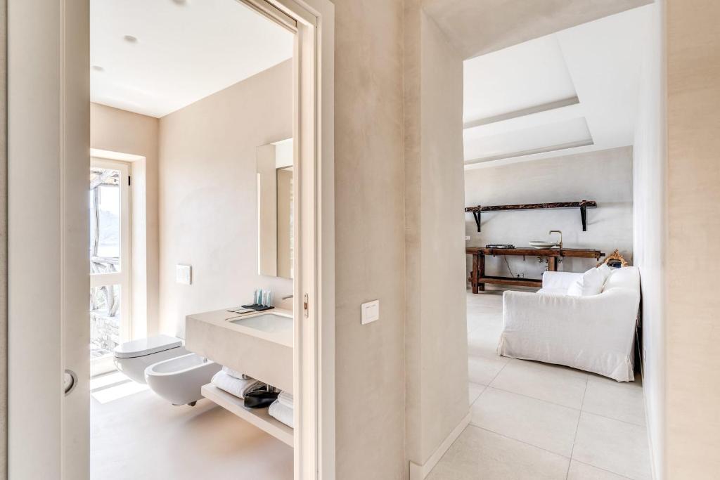 - une salle de bains blanche pourvue d'un lavabo et d'un lit dans l'établissement Villa Neranite Nerano Bay Views Pool & Jacuzzi by Feeling Italy, à Nerano