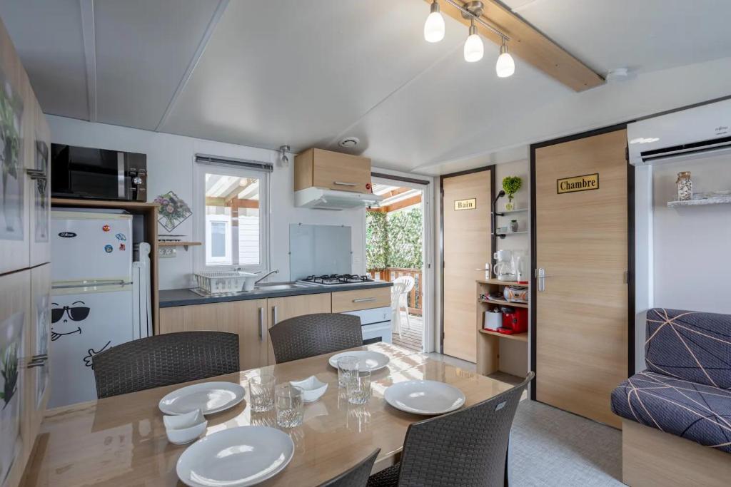 une cuisine et une salle à manger avec une table et des chaises dans l'établissement Mobil home proche du paradis des plages, à Saint-Jean-de-Monts
