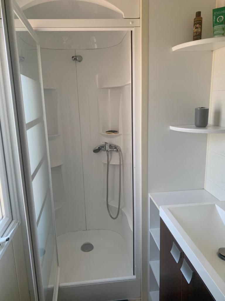 une douche avec une porte vitrée dans une salle de bain dans l'établissement Flo mobil home camping Poney trois étoiles route de Moustiers Ste Croix, à Sainte-Croix-de-Verdon