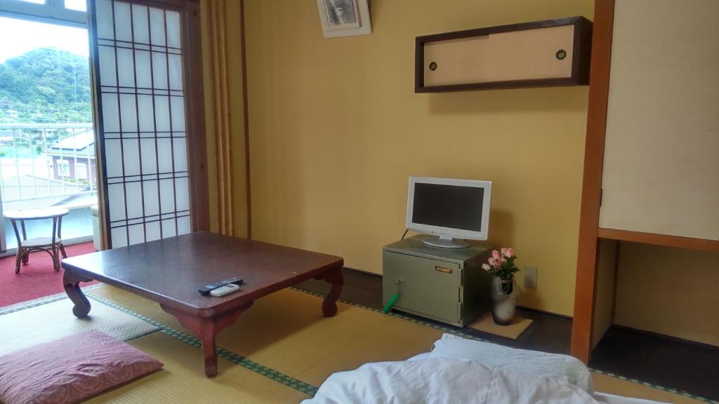 un salon avec une table et une télévision dans l'établissement Yoshioka Ryokan, à Kamogawa