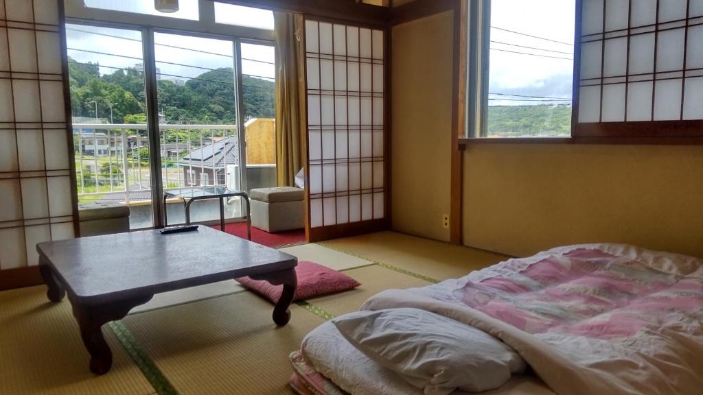 Cette chambre comprend une table, un lit et une fenêtre. dans l'établissement Yoshioka Ryokan, à Kamogawa