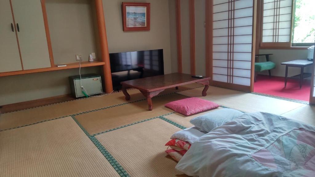 un salon avec un lit et une table dans l'établissement Yoshioka Ryokan, à Kamogawa