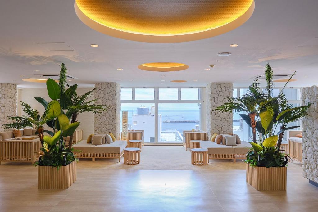 un hall avec des canapés et des plantes dans un bâtiment dans l'établissement Ooedo Onsen Monogatari Premium Atami, à Atami