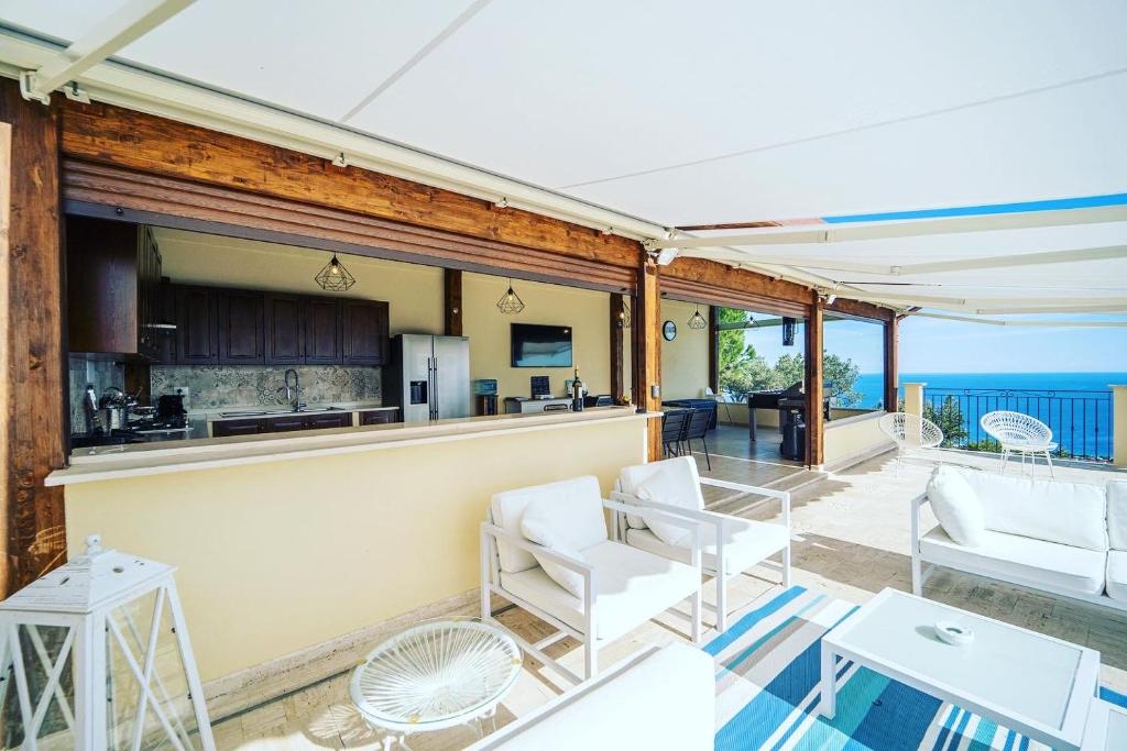 d'une terrasse avec des chaises blanches et un bar donnant sur l'océan. dans l'établissement Villa le Fontanelle, à Gasperina