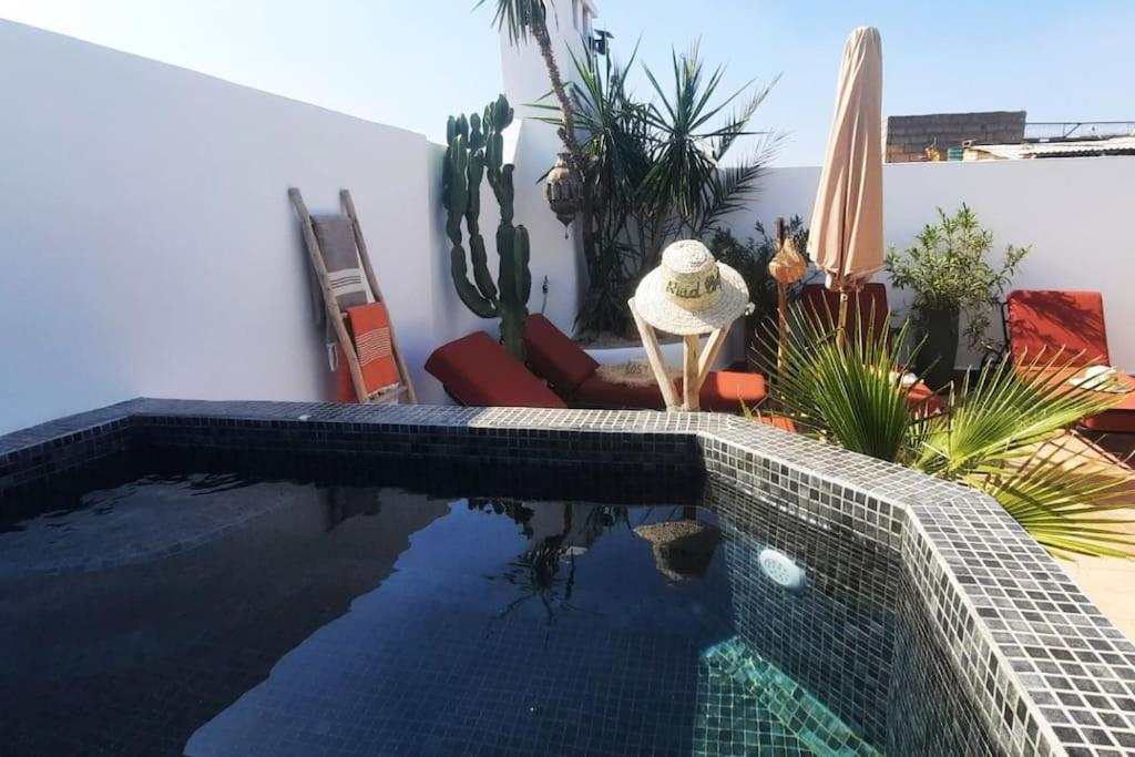 - une piscine avec des cactus et des plantes à côté d'une maison dans l'établissement Riad Cosy, à Marrakech