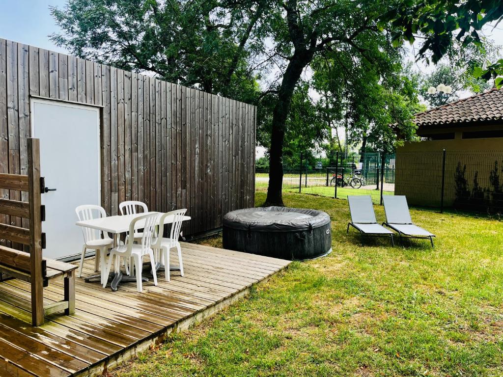 une terrasse en bois avec une table, des chaises et un tonneau dans l'établissement Camping de Bernadou - Le Lodge, à Villemur-sur-Tarn