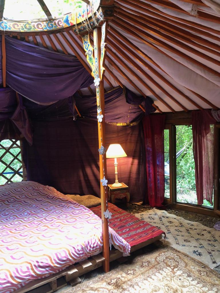 - une chambre avec un lit à baldaquin et une lampe dans l'établissement Yourte dans la forêt, à Rennes-les-Bains