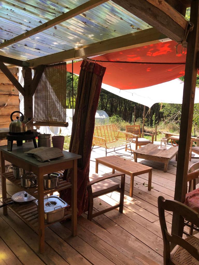 une terrasse en bois avec une table et des chaises ainsi qu'une tente dans l'établissement Yourte dans la forêt, à Rennes-les-Bains
