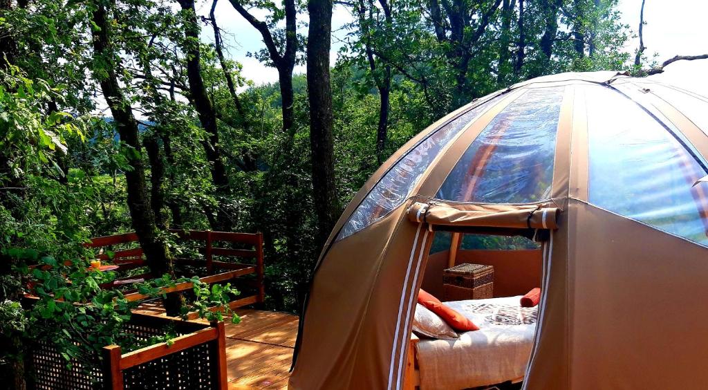 Une tente est installée sur une terrasse dans les bois. dans l'établissement Le Mobil'Dôme à Marie, à Cambounès