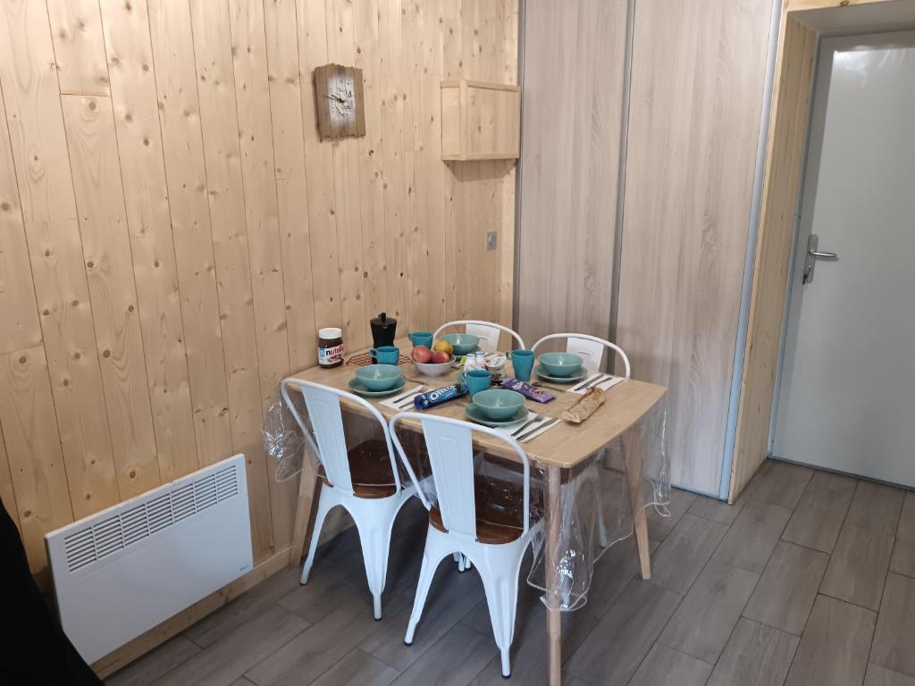 une table de salle à manger avec des chaises blanches autour dans l'établissement Appartement plein sud, Val Thorens Centre, à Val Thorens