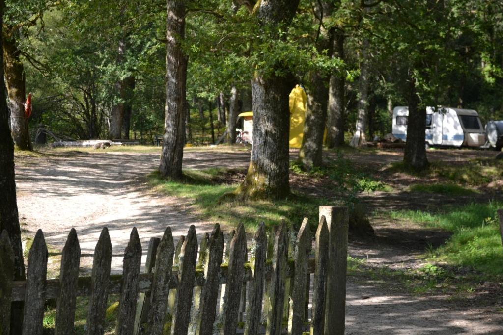 une clôture en bois dans un parc arboré dans l'établissement air naturel de camping moulin de malesse caravane, à Saint-Privat