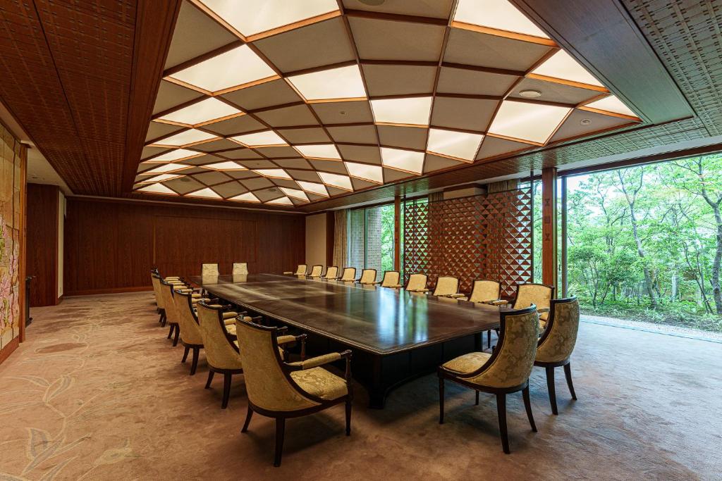 une grande salle de conférence avec une grande table et des chaises dans l'établissement 旅亭 半水盧, à Unzen