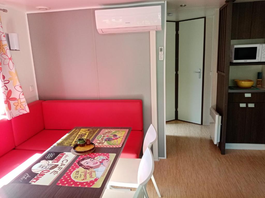 Cette petite chambre comprend un canapé rouge et une table. dans l'établissement Mobil-home, à Beynes