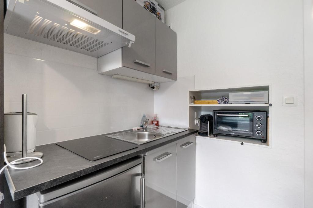 une petite cuisine avec un évier et un micro-ondes dans l'établissement Appartement Cosy- Villarembert, à Villarembert