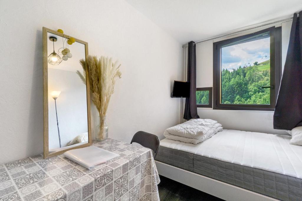 Cette chambre comprend un lit, un miroir et une fenêtre. dans l'établissement Appartement Cosy- Villarembert, à Villarembert