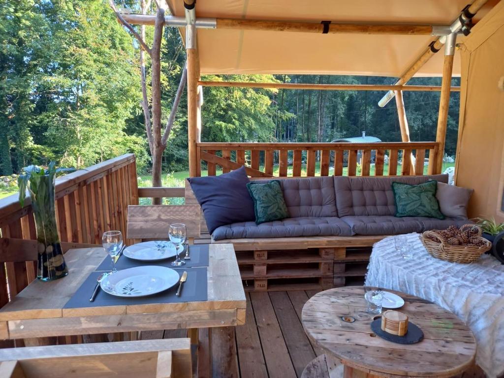 un patio avec un canapé et des tables sur une terrasse dans l'établissement LA TENTE DU RANDONNEUR, à Rimbach-près-Masevaux