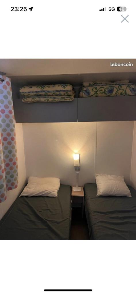 Cette petite chambre comprend deux lits et une lampe. dans l'établissement Camping la sainte baume, à Nans-les-Pins