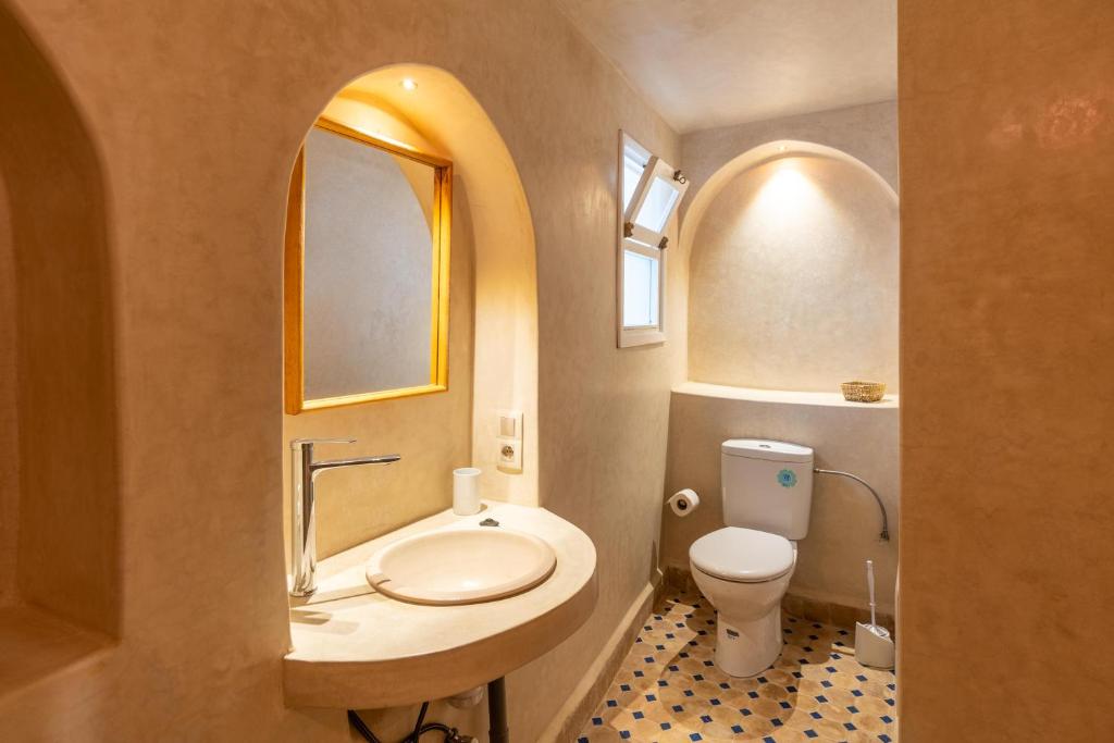 une salle de bain avec un lavabo, des toilettes et un miroir dans l'établissement Dar khadija, à Essaouira