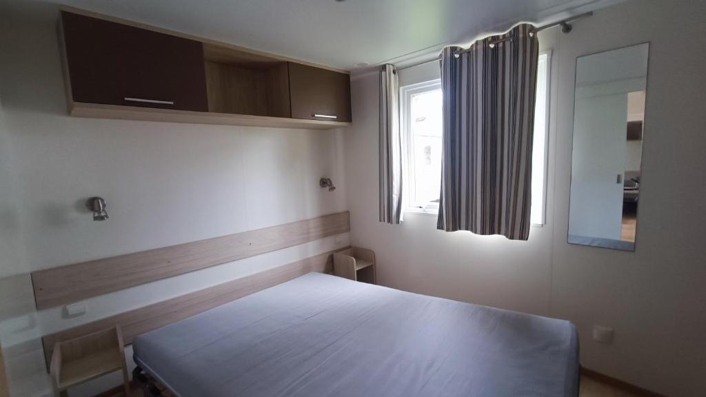 une chambre avec un lit blanc avec une fenêtre dans l'établissement Mobil Home climatisé 3 chambres 6 Pers Tout Confort 510PM, à La Boissière-de-Montaigu