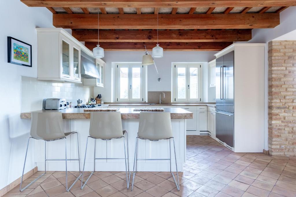 une cuisine avec des armoires blanches et un comptoir avec des tabourets dans l'établissement Villa Corte degli Ulivi, à Santa Maria Nuova