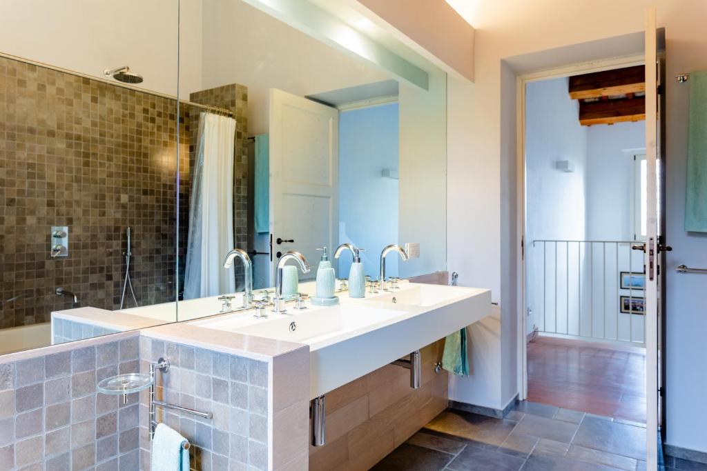 une salle de bain avec deux lavabos et un grand miroir dans l'établissement Villa Corte degli Ulivi, à Santa Maria Nuova