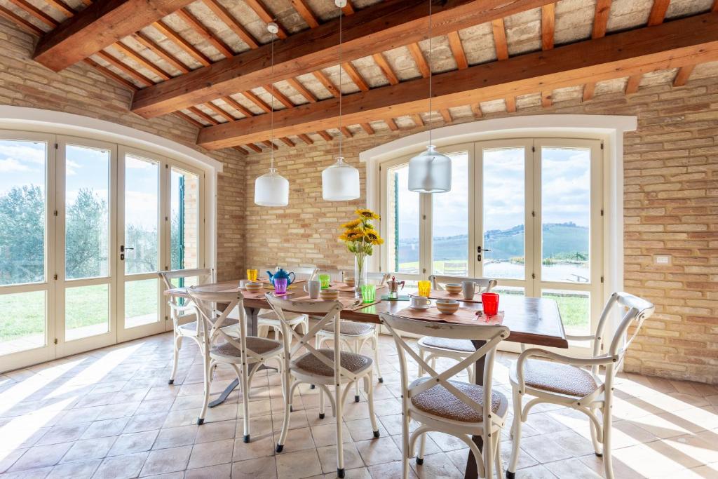 une salle à manger avec une table, des chaises et des fenêtres dans l'établissement Villa Corte degli Ulivi, à Santa Maria Nuova