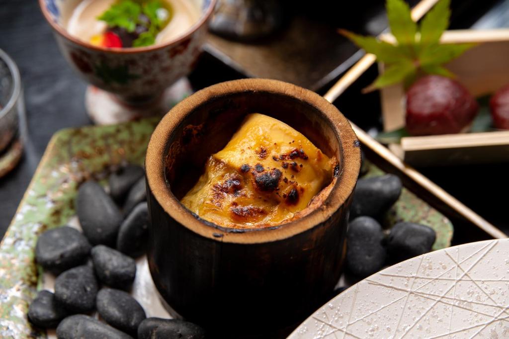 un bol de nourriture sur une table avec une assiette dans l'établissement Tsukasa Ryokan, à Saga