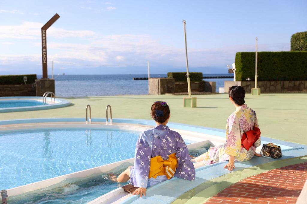 deux femmes en kimono assises au bord d'une piscine dans l'établissement Ooedo Onsen Monogatari Toi Marine Hotel, à Izu