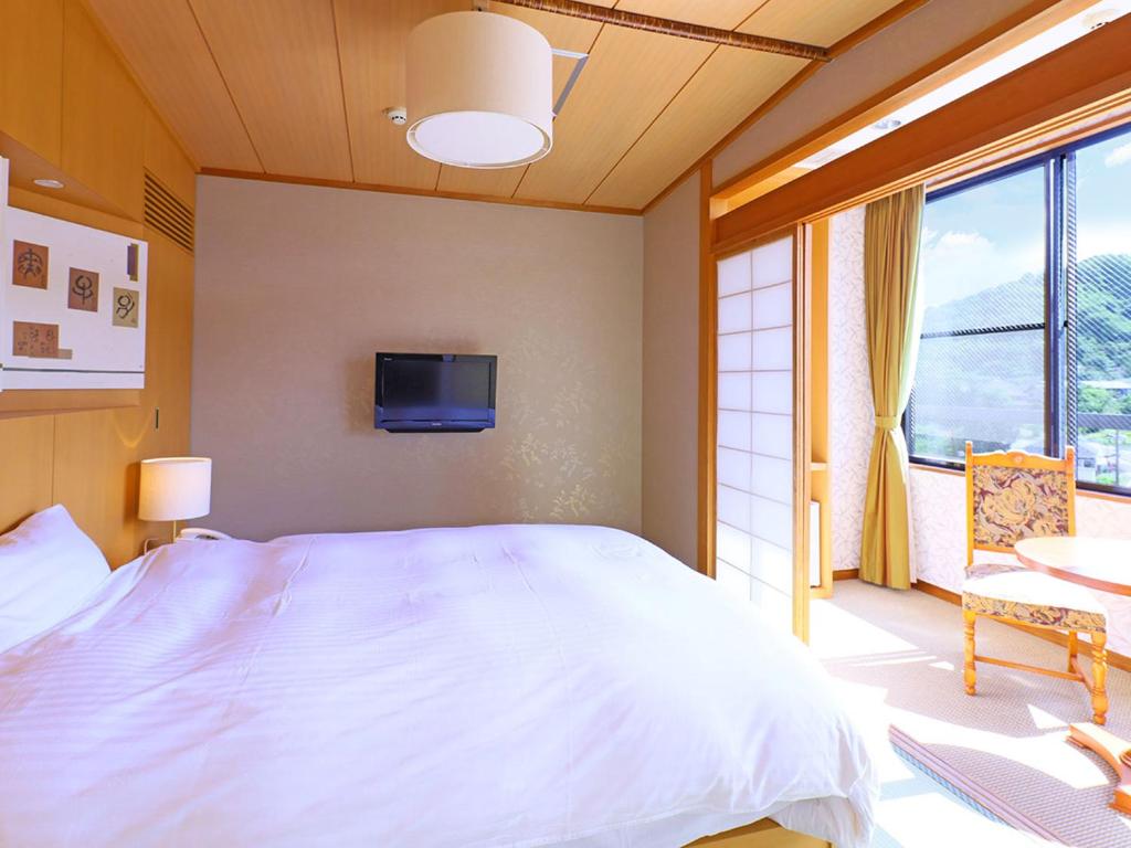 une chambre avec un grand lit blanc et une télévision dans l'établissement TAOYA Akiu, à Sendai