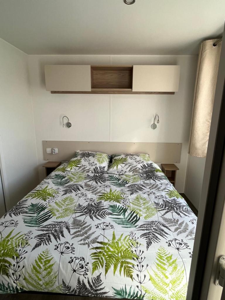 - une chambre avec un lit et une couette verte et blanche dans l'établissement Mobilhome 6 8 pers Les Dunes de Contis, à Saint-Julien-en-Born 10 autres photos