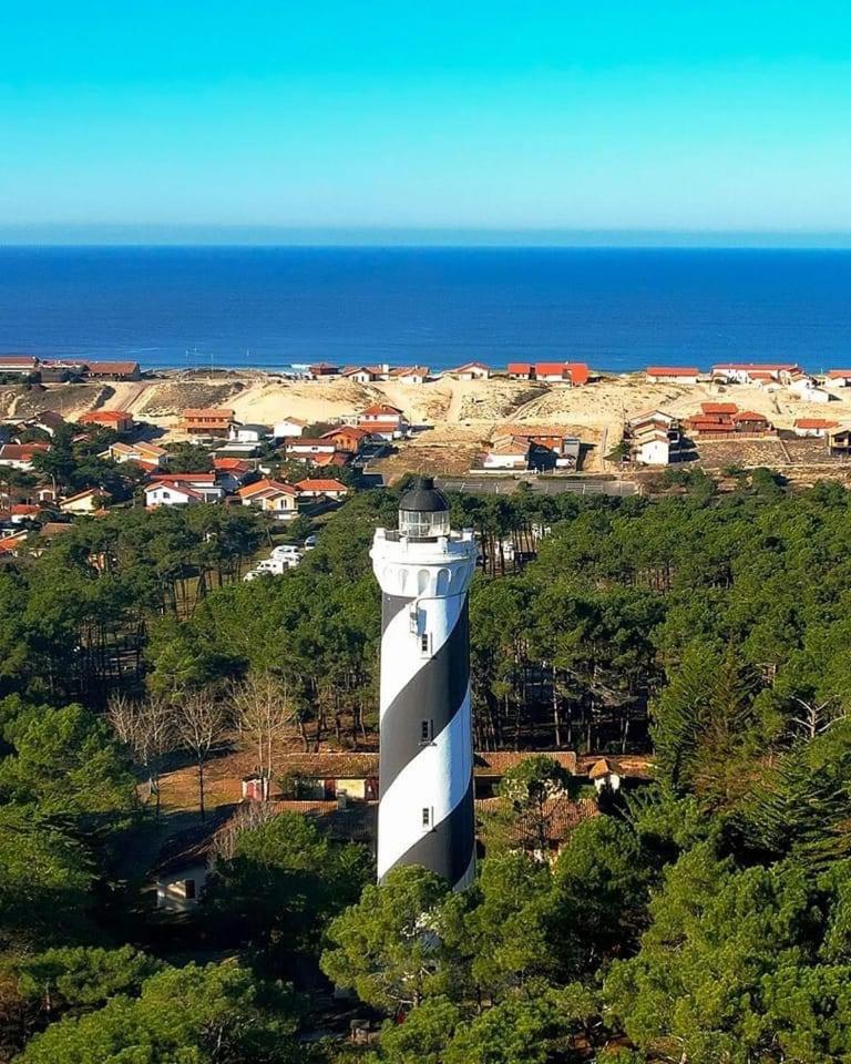 une tour blanche assise au sommet d'une colline à côté de l'océan dans l'établissement Mobilhome 6 8 pers Les Dunes de Contis, à Saint-Julien-en-Born