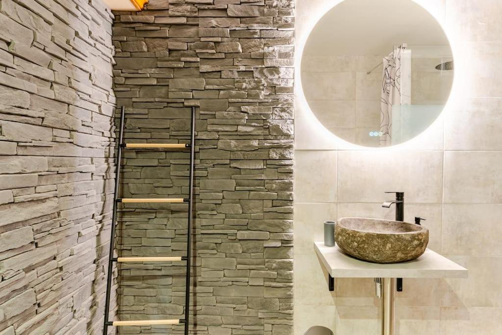une salle de bain avec un lavabo et un mur en pierre dans l'établissement Le 36/Espace bien-être privatif, à Bellevaux