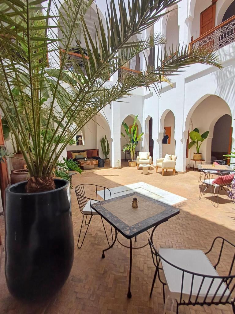 une cour avec une table et une plante en pot dans l'établissement Riad Miski, à Marrakech