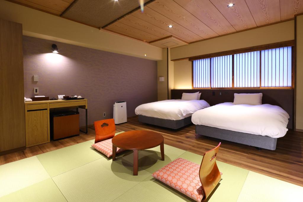 Cette chambre comprend deux lits, une table et une cuisine. dans l'établissement Suwakoen, à Suwa