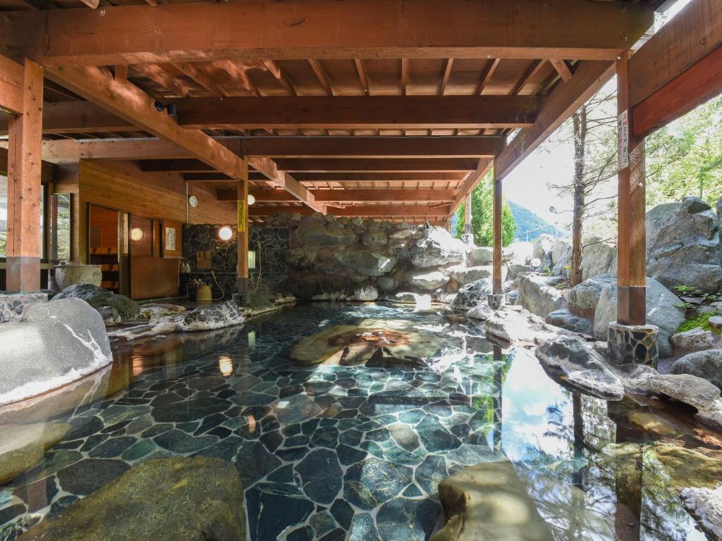 une piscine au milieu d'une maison avec des rochers dans l'établissement Iwazonokan, à Minami Alps