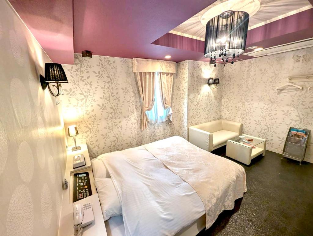 une chambre avec un lit blanc et une chaise dans l'établissement HOTEL ベアーズadults only, à Tenri
