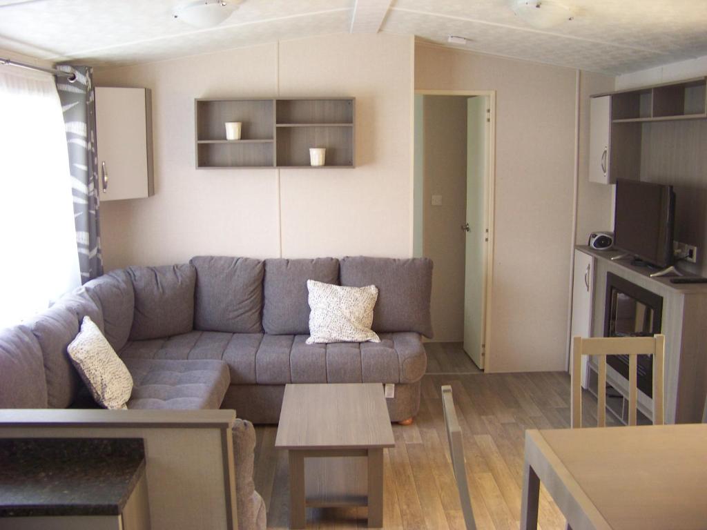 un salon avec un canapé et une table dans l'établissement Mobil home Céleste 6-8 personnes, à Litteau