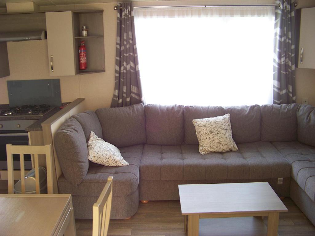 un salon avec un canapé et une table dans l'établissement Mobil home Céleste 6-8 personnes, à Litteau