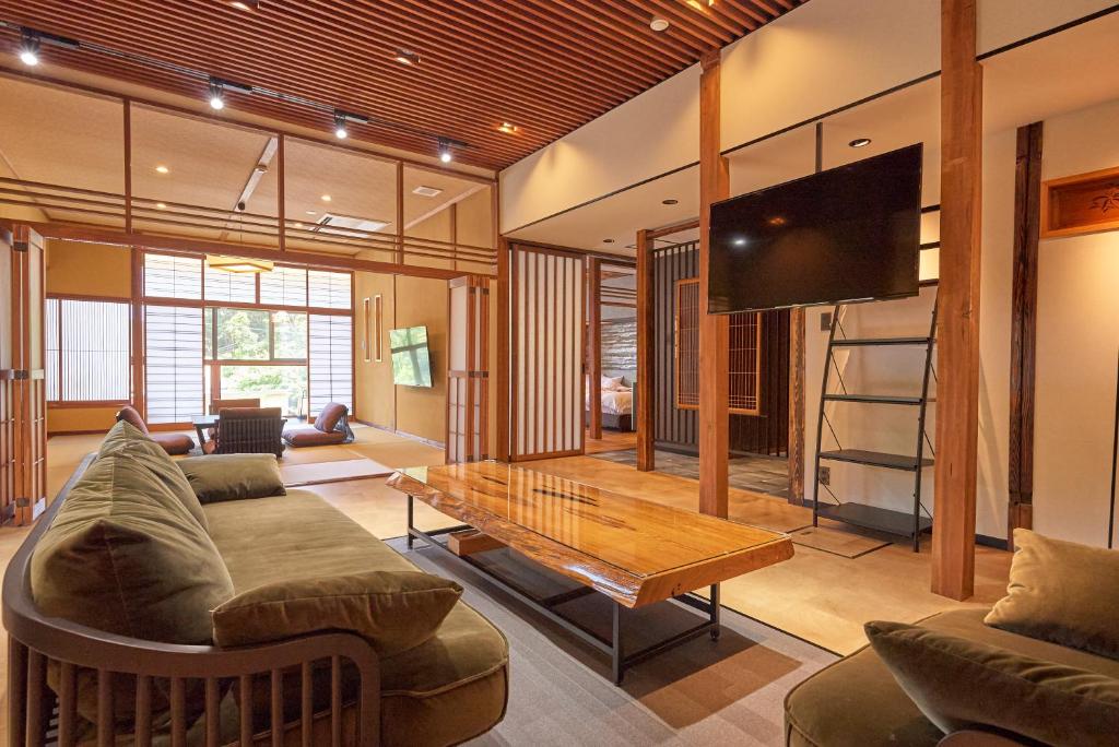 un salon avec un canapé, une table et une télévision dans l'établissement Arifuku Onsen Yoshidaya, à Gotsu