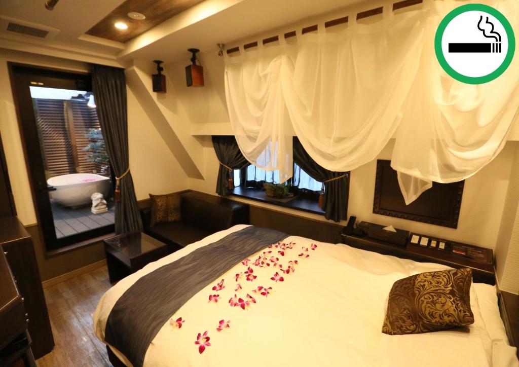 - une chambre avec un lit et une fenêtre fleurie dans l'établissement HOTEL PetitBali Higashi-Shinjuku, à Tokyo