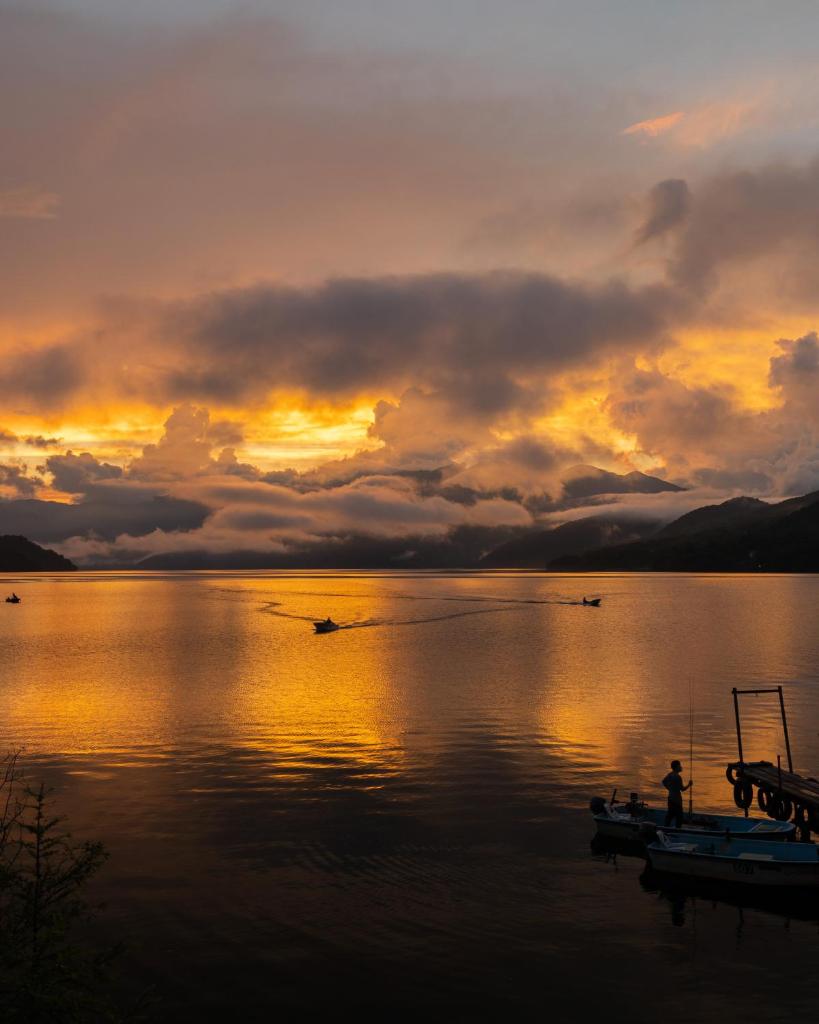 un coucher de soleil sur un lac avec des bateaux dans l'eau dans l'établissement Hatago Nagomi, à Nikkō